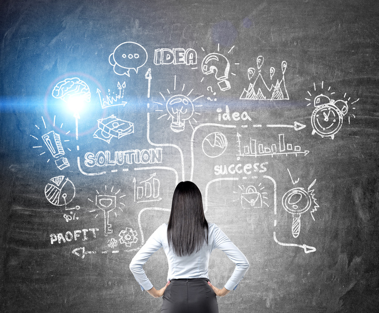 woman looking at chalkboard with illuminated business strategy